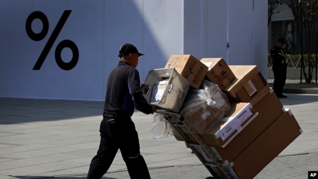 一名中国工人2019年4月4日用推车把货物送进北京一家商场。