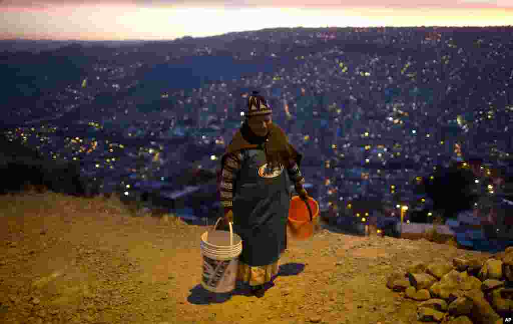 A woman walks with two buckets to wait for water to arrive near her neighborhood in La Paz, Bolivia, Nov. 16, 2016. President Evo Morales asked for forgiveness from La Paz residents for the water shortages caused by the worst drought in 25 years, and he acknowledged there will be no immediate solutions.