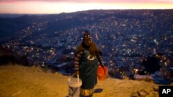 Une femme transportant deux seaux d'eau, La Paz, Bolivie, le 16 novembre 2016. 