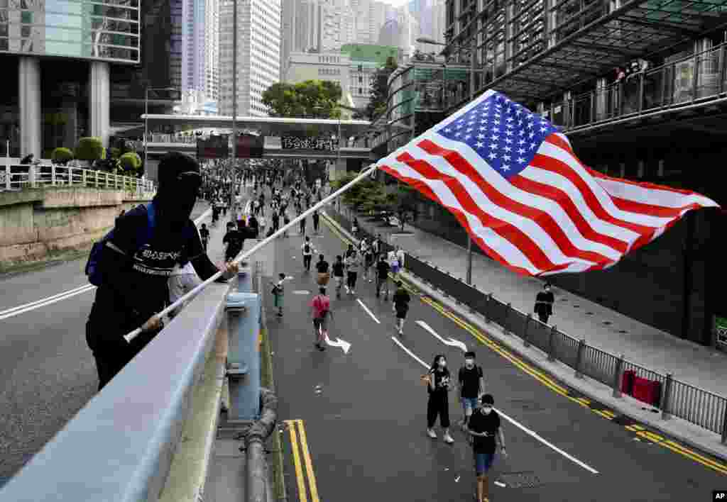 Manifestantes ondean banderas estadounidenses y gritan consignas mientras marchan desde Chater Garden al Consulado de Estados Unidos en Hong Kong, el domingo 8 de septiembre de 2019, en busca de apoyo internacional para su movimiento, un día después de que sus intentos de interrumpir el transporte al aeropuerto fueron frustrados por la policía. (Foto AP / Vincent Yu)