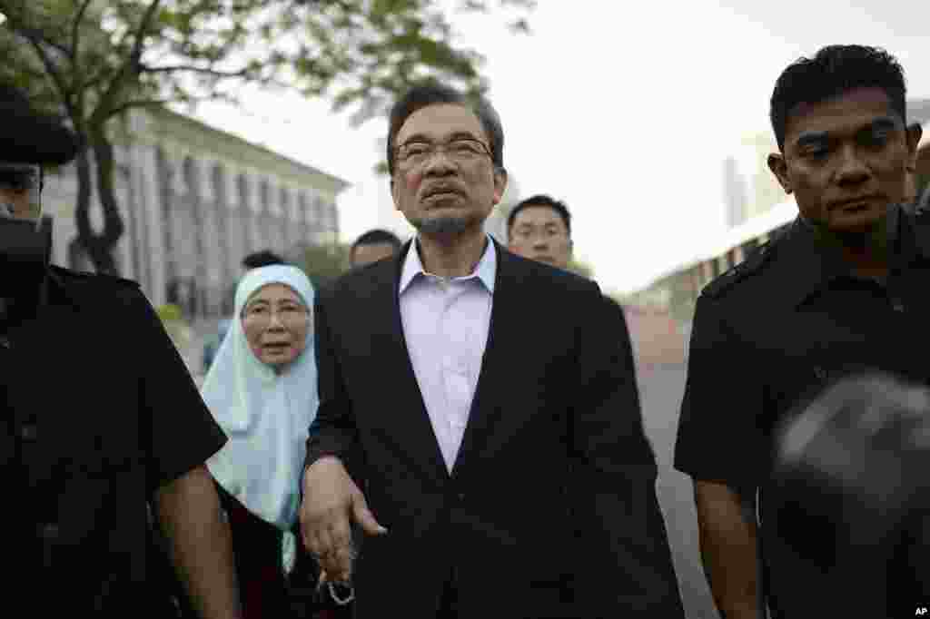 Malaysian opposition leader Anwar Ibrahim, center, walks with his wife Wan Azizah as they arrive for his final hearing of his sodomy conviction in Putrajaya, Malaysia, Tuesday, Oct. 28, 2014.