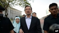 Malaysian opposition leader Anwar Ibrahim, center, walks with his wife Wan Azizah as they arrive for his final hearing of his sodomy conviction in Putrajaya, Malaysia, Tuesday, Oct. 28, 2014.