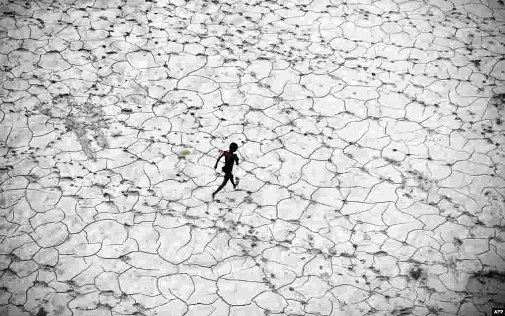 An Indian child plays in a dry river bed after flood waters receded in Allahabad.