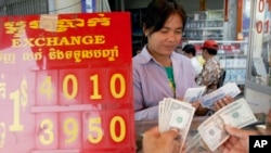 FILE - A currency trader counts Cambodian riels to exchange for U.S. dollars at a money exchange stall in the capital Phnom Penh, Cambodia, Feb. 15, 2008. Cambodia racked up $278 million in U.S. loans under the Lon Nol government in the 1970s.