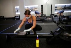 Employee of CITYROW Atlanta Midtown, Ellie Klarl, cleans the equipment after a class as gyms reopen with limited members on Saturday, May 16, 2020, amid the COVID-19 virus in Atlanta.