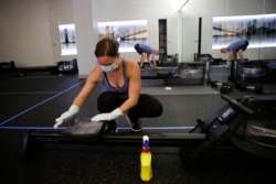Employee of CITYROW Atlanta Midtown, Ellie Klarl, cleans the equipment after a class as gyms reopen with limited members on Saturday, May 16, 2020, amid the COVID-19 virus in Atlanta.