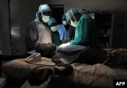 FILE - Evan Atar Adaha performs a surgery on a Sudanese youth at a hospital in Kurmuk region of Sudan's Blue Nile state, Oct. 10, 2011.