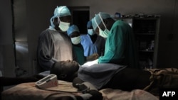 FILE - Evan Atar Adaha performs a surgery on a Sudanese youth at a hospital in Kurmuk region of Sudan's Blue Nile state, Oct. 10, 2011.