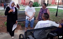 In this Monday, June 18, 2018, photo, attorney Tahirah Amatul-Wadud, left, who is challenging incumbent U.S. Rep. Richard Neal, D-Mass., greets residents of an apartment complex while campaigning in Springfield, Mass.