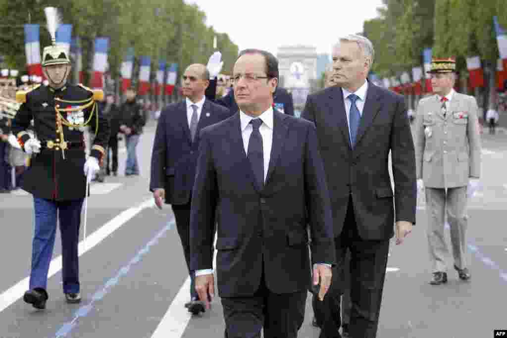 France's President Francois Hollande (C), Prime Minister Jean-Marc Ayrault (2ndR) and Junior Minister for Veterans Kader Arif (2dnL), walk on the Champs-Elysees avenue during the annual Bastille Day military parade in Paris, on July 14, 2012