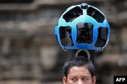 A Cambodian technician carries a back-packa mounted with a device housing 15 cameras as he demonstrates the technique used to digitally map the Angkor Wat temple, part of the Angkor architectural complex in north-western Cambodia on April 3, 2014.