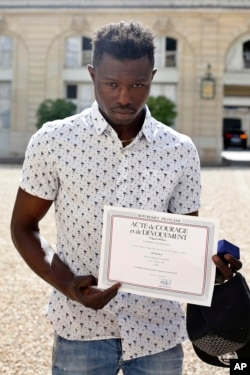 Mamoudou Gassama displayed a certificate of courage and dedication signed by Paris Police Prefect Michel Delpuech as he leaves the presidential Elysee Palace after his meeting with French President Emmanuel Macron, in Paris, May, 28, 2018.