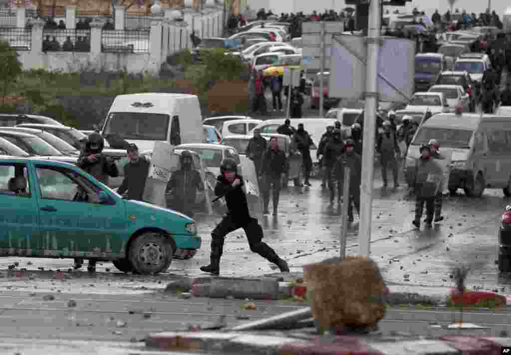 Riot police clash with protesters next to the cemetery where thousands of Tunisians gathered to attend the funeral of slain opposition leader Chokri Belaid, near Tunis, Feb. 8, 2013.