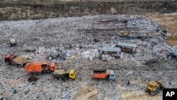 In this photo taken on Friday, April 20, 2018, garbage trucks unload the trash at the Volovichi landfill near Kolomna, Russia. Thousands of people are protesting the noxious fumes coming from overcrowded landfills surrounding Moscow.