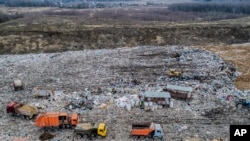 In this photo taken on Friday, April 20, 2018, garbage trucks unload the trash at the Volovichi landfill near Kolomna, Russia. Thousands of people are protesting the noxious fumes coming from overcrowded landfills surrounding Moscow, blaming them for caus