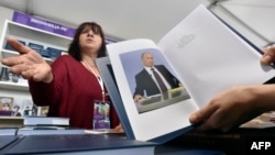 A customer holds a copy of Russian President Vladimir Putin's book "Direct speech" as she speaks with a vendor (L) at the Red Square Book Festival in Moscow on June 3, 2016.