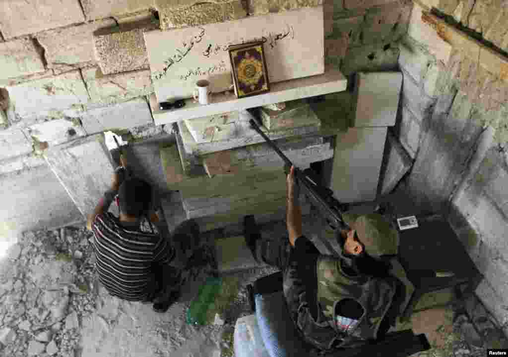 Members of the Free Syrian Army aim their weapons as they take up a defensive position in Aleppo's Salaheddine district, Syria, June 25, 2013. 