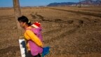 Một phụ nữ Triều Tiên cõng con đi ngang cánh đồng lúa gần Suriwon. Triều Tiên đã phải vật lộn với tình trạng thiếu lương thực kinh niên trong nhiều thập niên.