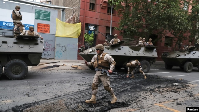 Soldados chilenos patrullan una calle de Santiago el domingo 20 de octubre de 2019, luego del toque de queda declarado por el gobierno el sábado por la noche. Reuters, Iván Alvarado.