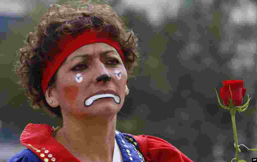 A professional clown, whose son has gone missing, holds a flower at a monument honoring mothers, where many gathered after participating in the National March for Dignity on the day Mexicans celebrate Mother&#39;s Day in Mexico City, May 10, 2014.