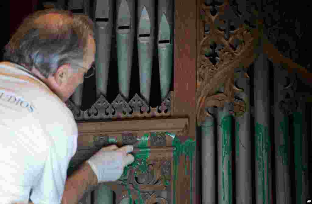 William Adair of Gold Leaf Studios removes green paint from the organ in the Washington National Cathedral's historic Bethlehem Chapel, July 30, 2013. 