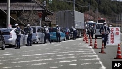 Police officers stop cars at a checkpoint near the town of Namie, Fukushima Prefecture, northeastern Japan, April 21, 2011