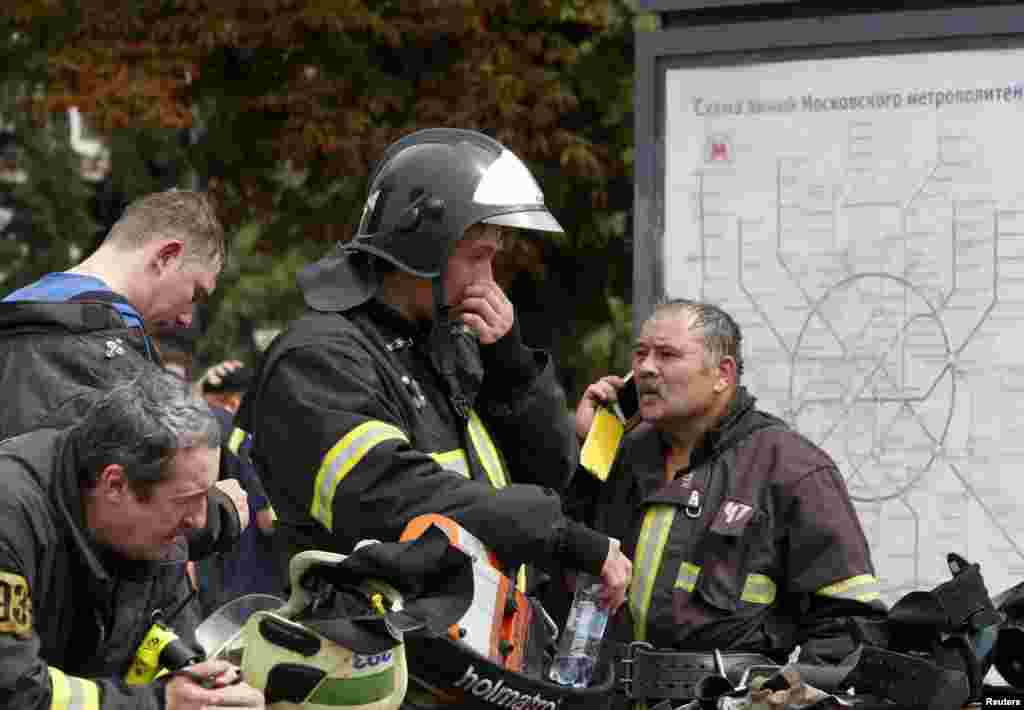 Members of the emergency services stand near a map of metro train lines outside the station following an accident on the subway, in Moscow, July 15, 2014.