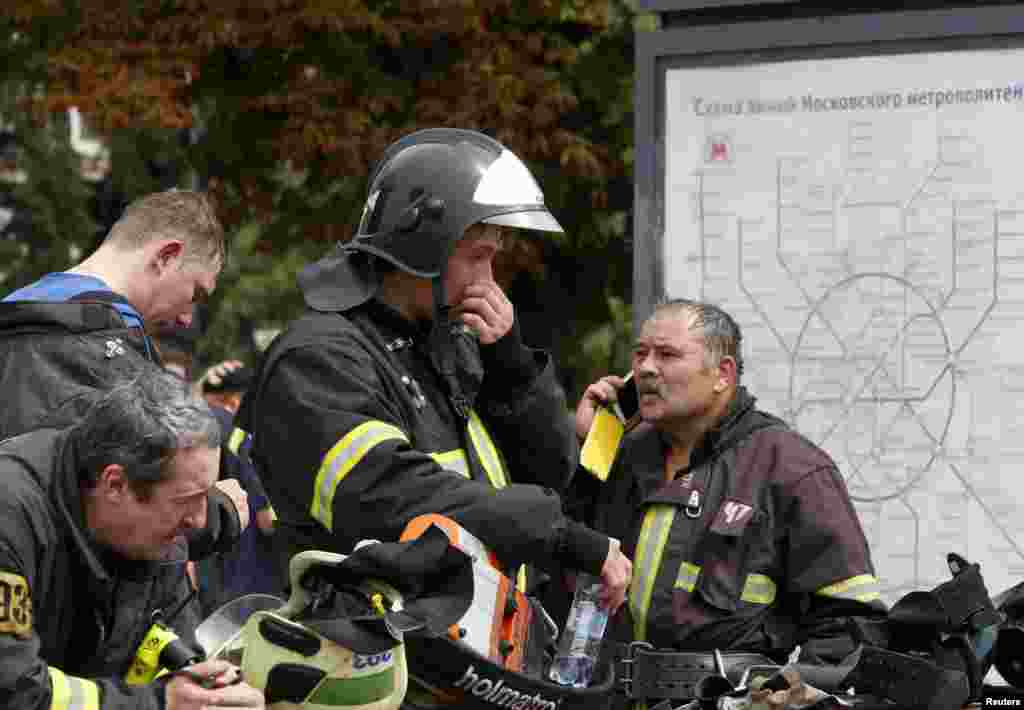 Members of the emergency services stand near a map of metro train lines outside the station following an accident on the subway, in Moscow, July 15, 2014.