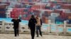 FILE - Security guards walk in front of containers at the Yangshan Deep Water Port in Shanghai, April 24, 2018.