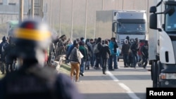 French riot police chase migrants from U.K.-bound lorries making their way to the ferry terminal in Calais, Oct. 22, 2014.