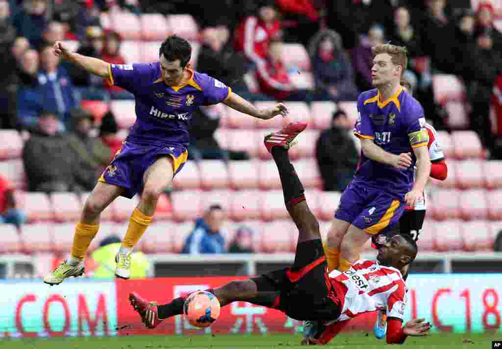 Sunderland's El-Hadji Ba, bottom, vies for the ball with Kidderminster Harriers' Jack Dyer, left, and captain Kyle Storer, right, during their English FA Cup fourth round soccer match at the Stadium of Light, Sunderland, England.