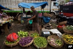 FILE - A vegetable seller sprinkles water on vegetables to stop them from drying out at a market in Gauhati, India, June 16, 2016.