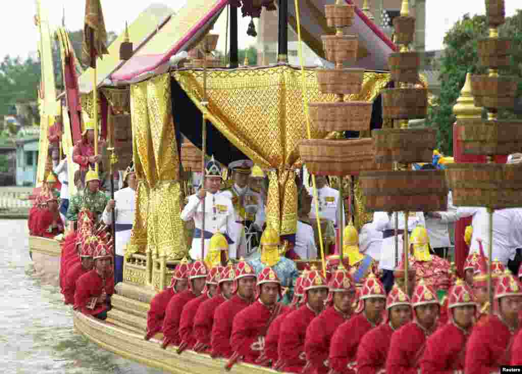 Raja Bhumibol Adulyadej (tengah) duduk di atas tongkang kerajaan dalam prosesi di Sungai Chao Phraya di Bangkok, 1999.