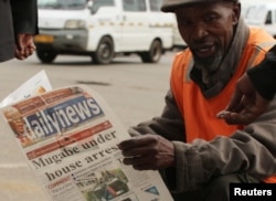 A street vendor reads a newspaper in central Harare, Zimbabwe, Nov. 16, 2017.