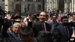 Peru's President Martin Vizcarra holds up a folder as he waves next to next to Prime Minister Cesar Villanueva, left, as they leave the government palace for Congress where he plans to urge legislators to declare an emergency at the attorney general's office, Jan. 2, 2018.