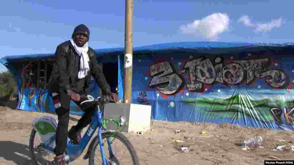 Un migrant fait du vélo dans la &quot;jungle&quot; qui est le nom du camp situé aux abords de Calais dans le nord de la France, 13 octobre 2015 (Nicolas Pinault/VOA). &nbsp;