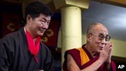 Lobsang Sangay, left, the new prime minister of Tibet's government in exile, stands next to Tibetan spiritual leader the Dalai Lama as he greets the crowd at his swearing-in ceremony at the Tsuglakhang Temple in Dharmsala, India, Monday, Aug. 8, 2011.