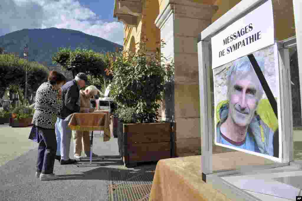 Residents of St. Martin Vesubie, southern France, sign a tribute album to pay respect to French mountaineer, Herve Gourdel, after he was beheaded by militants in Algeria the day before, Sept. 25, 2014. 