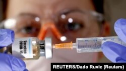 FILE PHOTO: A woman holds a small bottle labeled with a "Vaccine COVID-19"