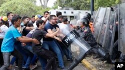 委內瑞拉大學生在首都卡拉卡斯一次反馬杜羅政府示威中試圖奪走防暴警察的防護盾。（美聯社：2019年11月14日）
