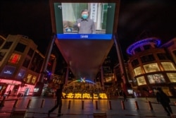北京一家商场的电视屏幕上显示中央电视台播放的中国国家主席习近平视察武汉火神山医院的画面。（2020年3月10日）