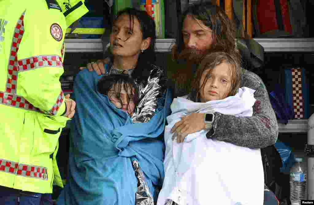 A family receives medical attention after being by the Marine Rescue boat as the state of New South Wales experiences widespread flooding and severe weather, in the suburb of Sackville North in Sydney, Australia.