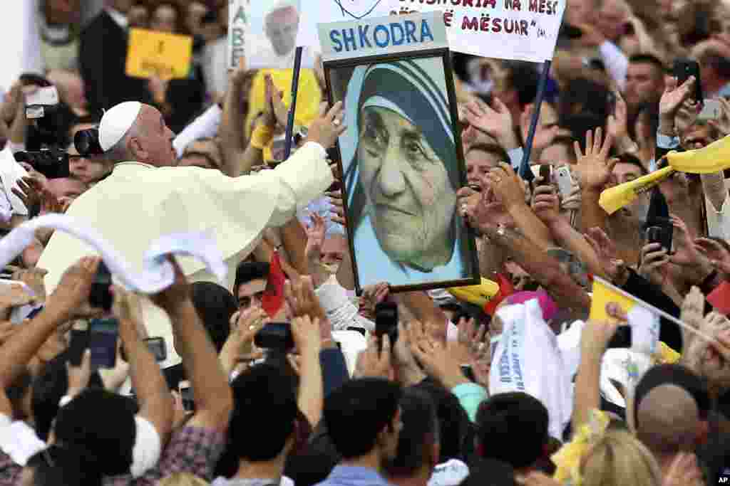 Pope Francis reaches for a poster of Mother Teresa as he is driven through the crowd, in Tirana, Albania.