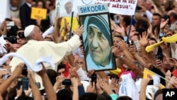 FILE - Pope Francis reaches for a poster of Mother Teresa as he is driven through the crowd, in Tirana, Sunday, Sept. 21, 2014. 