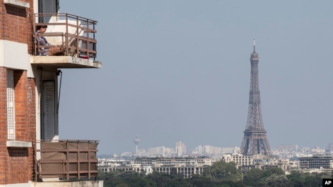 A woman enjoys the sun on her balcony as the Eiffel Tower is clearly seen in the background during the nationwide confinement to ｃounter the conoravirus in Saint-Cloud, west of Paris, Wednesday, April 22, 2020. Air pollution has fallen in Paris in respons