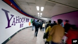 FILE - Chinese subway riders walk past a Yahoo advertisement at a metro station in Beijing.
