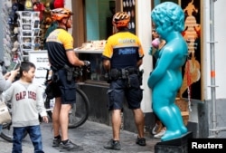 FILE - Belgian police officers are seen next to a replica of Brussels' iconic Manneken Pis statue during a patrol in central Brussels, Belgium, May 31, 2017.