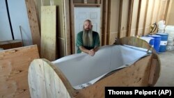 Co-owner of The Natural Funeral, Seth Viddal, stands next to his body composting vessel, 2021. (AP Photo/Thomas Peipert)