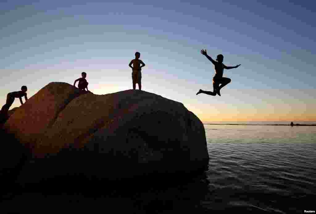 Anak-anak melompat ke pantai Camps Bay di Cape Town, Afrika Selatan.