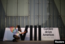 A woman cleans a banner ahead of the 8th Summit of the Americas in Lima, Peru, April 10, 2018.